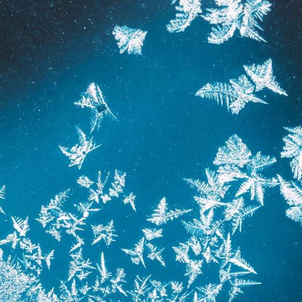 Frost forms on a window in a way that looks like snowflakes falling.