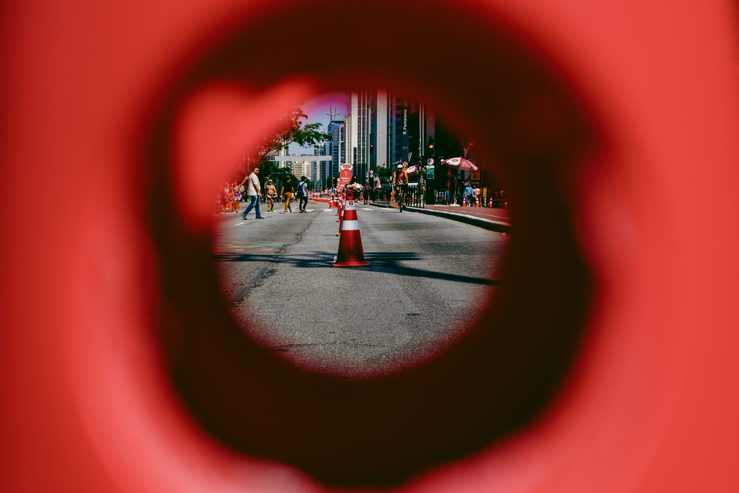 a view of a city street, with a pylon in the middle of the road, framed though the hole of a pylon