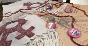 A collection of queer and activist ephemera is laid out on the table.