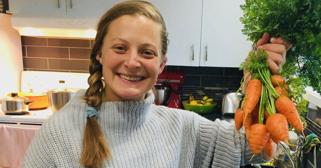 Ryan Cope holds up short stubby carrots from her garden, in her kitchen.