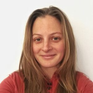 Ryan Cope profile photo of her red hair, smile, and dusty rose shirt. She is an editor and writer.