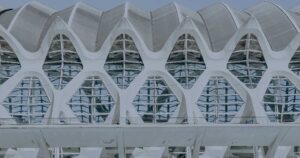 A very cool building full of wobbly holes and arches which is mostly white is sort of faded out with a blue sheen.