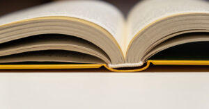 A book with a yellow cover sits on a table, open, with it's spine resting flat.